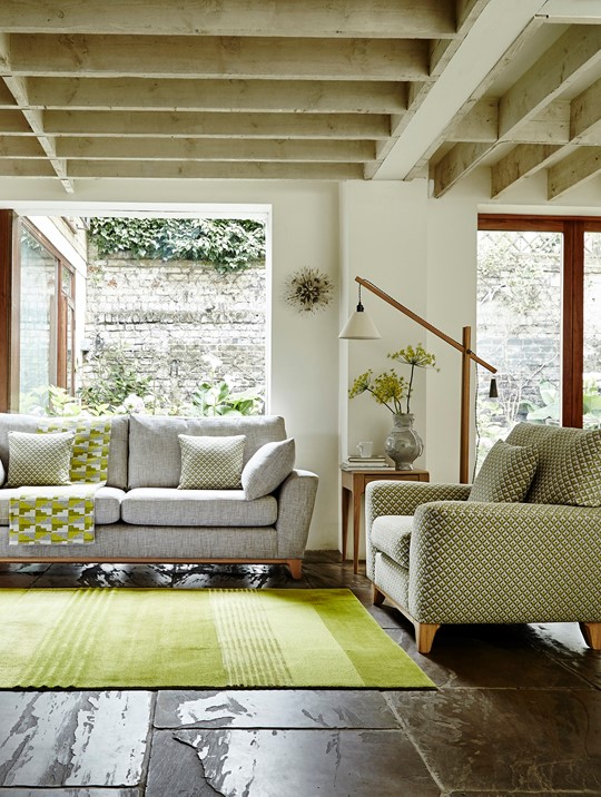 Ercol Grey Sofa with Yellow/Green Pillows and Throws and Green Accent Chair in a Bright Living Room with alot of Greenery
