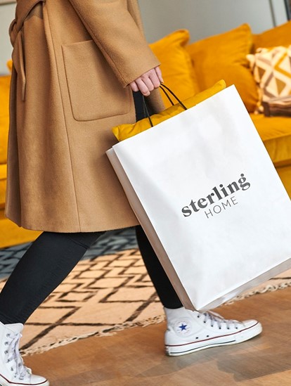 Girl is walking with Sterling Home branded shopping bag in hand in our Glasgow sofa shop